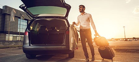 a man putting a suit and luggage in the back of a van