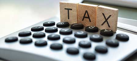 wooden blocks that spell tax on top of a calculator