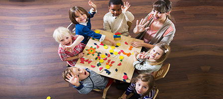 a group of kids sitting at a table waving