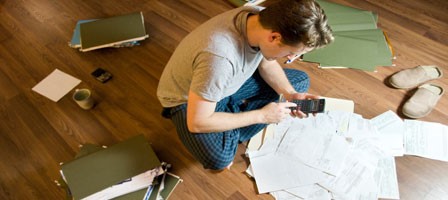 a man sitting on the floor with folders and documents surrounding him