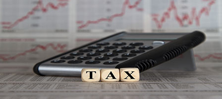 a calculator with wooden blocks in front of it with the word tax spelled out