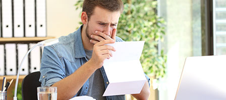 a man looking at a paper with a worried look 