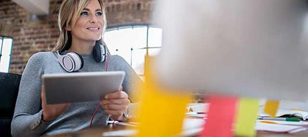 a woman sitting at a desk working on a ipad