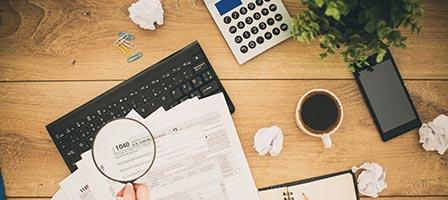 someone taking a magnifying glass to tax paperwork