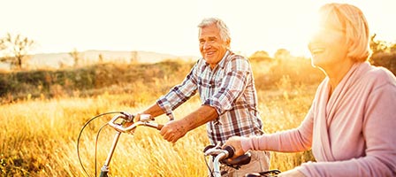 a man and woman riding bikes through a field