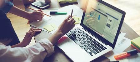 two people working with a laptop in front of them