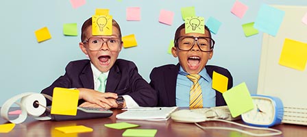 two kids playing with sticky notes at a desk