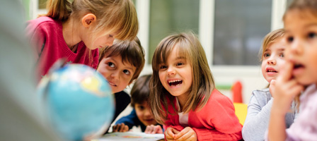 kids sitting at a table looking at a globe