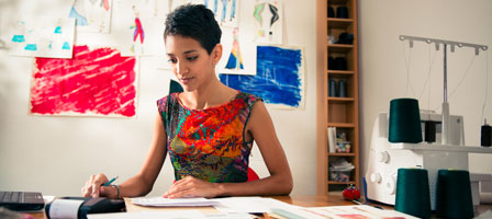 a woman sitting at a desk working on a calculator with documents in front of her