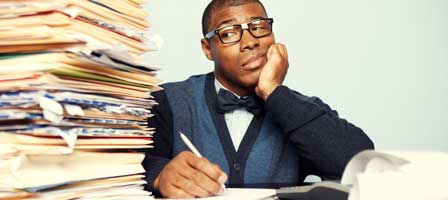 a man sitting at his desk looking at a pile of folders filled with paperwork