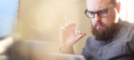 a man with a pen in his hand while he looks at something