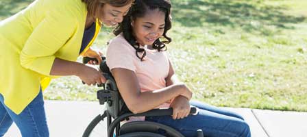 a woman pushing a teen in her wheelchair