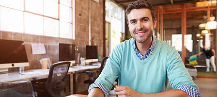 a man sitting at a desk smiling confidently