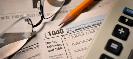 a pencil, glasses and a calculator on top of tax documents