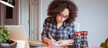 a woman working at her desk writing in a journal