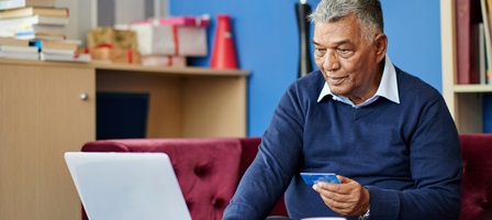 a man entering his card information into a laptop