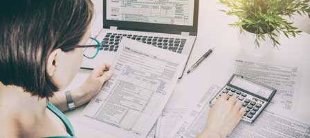 a woman looking at tax paperwork using a calculator