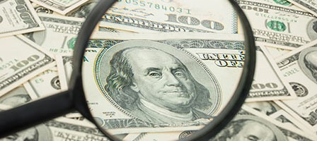 a magnifying glass looking at a pile of money