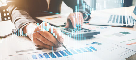 a man looking at charts with a caclulator in one hand and a pen in the other