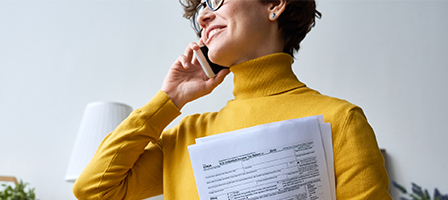 a woman talking on the phone with paperwork in her hands